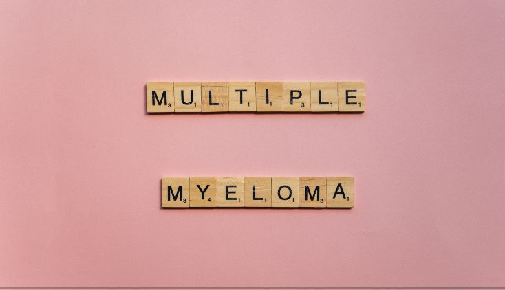 Scrabble tiles on a pink background that spell "multiple myeloma"