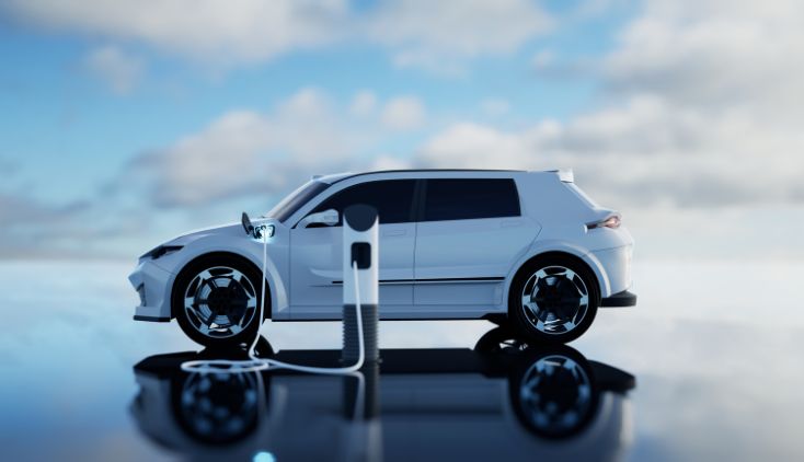 A white electric SUV parked at a charging station, with clouds in the background