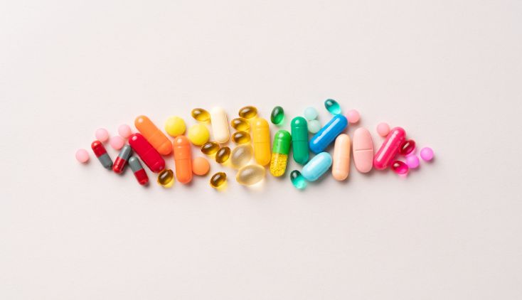 Various multi-colored pills on a white background.